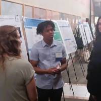 Ishmael Nash talking to a group of students about their poster presentation